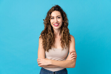Young caucasian woman isolated on blue background keeping the arms crossed in frontal position