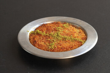 Turkish dessert kunefe, kunafa, kadayif with pistachio powder and cheese, served hot, very sweet. Turkish traditional dessert.