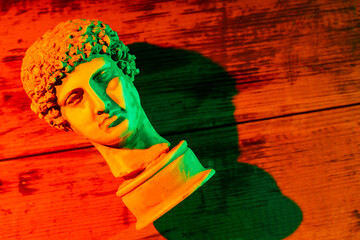 Gypsum copy of ancient statue Hermes head in orange green neon light. Neon image with ancient greek...