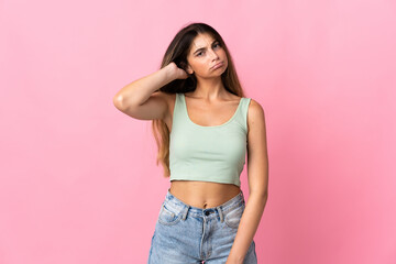 Young caucasian woman isolated on pink background having doubts