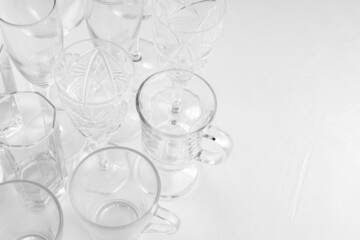 Set of assorted empty drink glasses on white background. Background of empty glasses on white table. Copy space. Top view