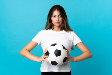 Young caucasian woman isolated on blue background with soccer ball