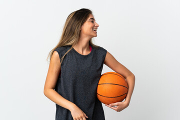 Young woman playing basketball isolated on white background laughing in lateral position