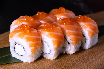philadelphia sushi with red caviar on a wooden board on a dark background