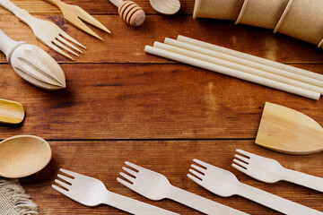 Different wooden kitchenware on wooden table. Wooden cutlery on old planks. Bamboo straws and disposable paper cups. Eco-friendly tableware. Zero waste concept. Top view
