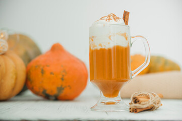 Cup with foam and cinnamon on background of pumpkins. Pumpkin autumn warming drink close-up and copy space...