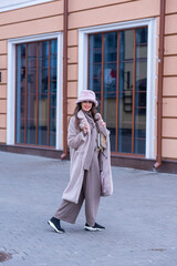 Naklejka premium beautiful caucasian girl walks in the city in winter in a fur coat and hat