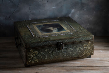 Green vintage jewelry box on wooden table against plastered wall background