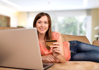 Naklejka premium Happy young woman shopping online, paying bills with credit card