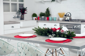 Empty plates with cutlery on red napkins close-up. Table decor for Christmas, New Year. Christmas garland with red balls on table..