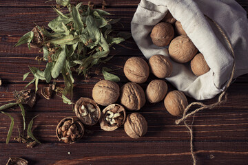 walnuts in a cotton bag and dried linden flowers on an old wooden table still life