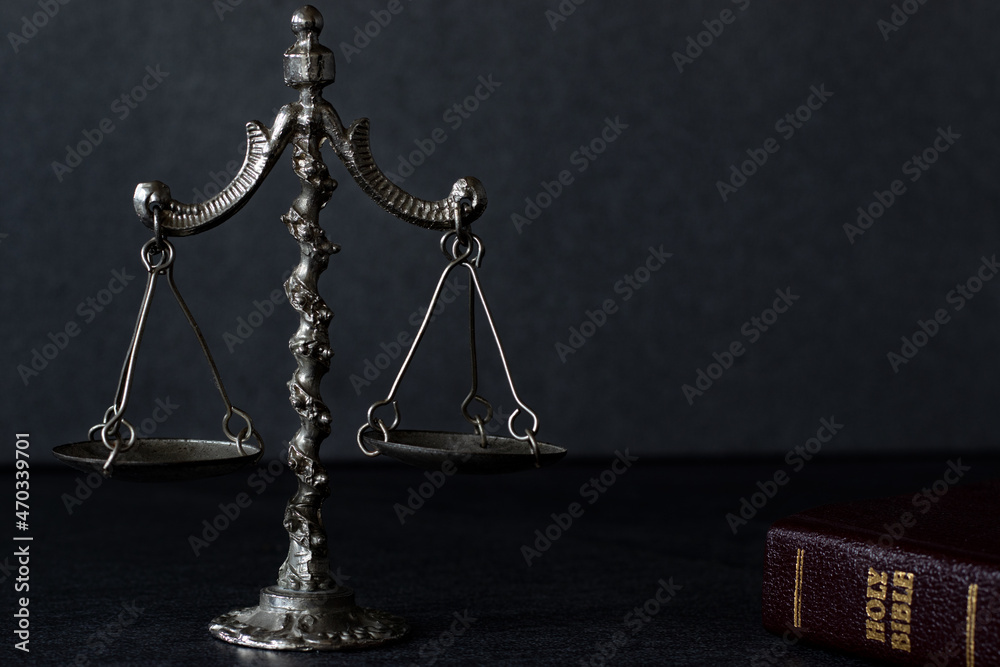 Wall mural Vintage weighing balance scale on dark background with closed Holy Bible Book. Christian biblical concept of Law and justice. Old ancient rustic symbol of comparison and measure. A close-up.