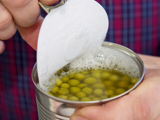 Male hands open a metal jar with food