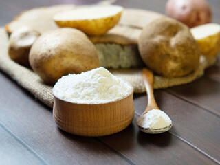 Potato starch with potatoes on a dark wooden background.