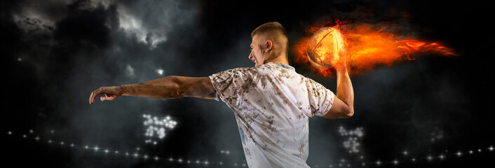 Man rugby player holds ball on fire background. Sports banner