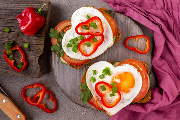 sandwich with tomatoes, cucumbers and egg in the shape of a heart on a board, purple napkin