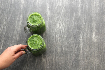 Green juice served in a mason jar with vegetables such as cucumber, chard, spinach, lemon and fruits for a healthy and nutritious breakfast
