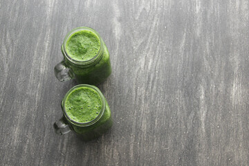 Green juice served in a mason jar with vegetables such as cucumber, chard, spinach, lemon and fruits for a healthy and nutritious breakfast
