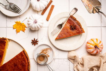 Piece of american pumpkin pie with cinnamon on white tile background, top view
