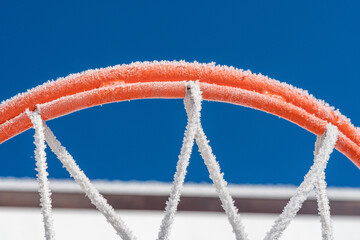 a close up of an orange frosted basketball hoop against blue sky