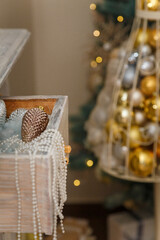 Merry Christmas decorated interior details. Drawer with shiny pine cone toy, pearl beads, artificial snow. Golden baubles, garlands bokeh