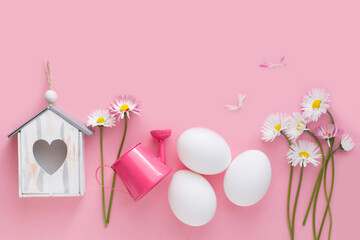 Easter background with eggs, spring flowers, birdhouse, watering can on pink paper
