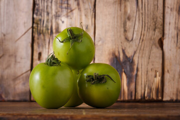 Heap of fresh unripe green tomatoes on brown wooden kitchen table. Local farmer fresh organic product. Vegan eco-friendly no animal food alternative