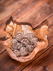 Round chocolates on a sheet of parchment paper. Wooden background from boards.