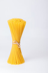 An upright bunch, a bunch of raw spaghetti tied with rope. Bundle on a white background. Italian food concept.