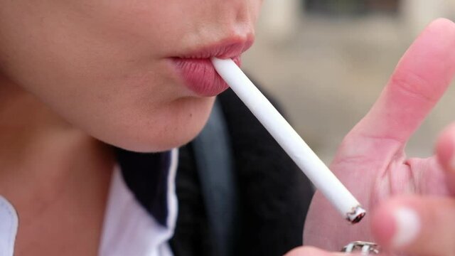 Close-up of woman lighting up cigarette with lighter. Woman smokes cigarette