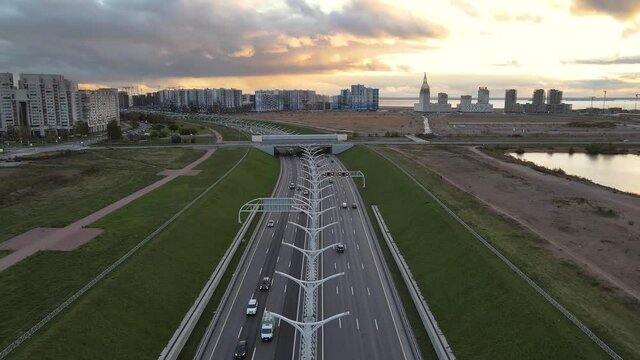 Fly over multilane road in city center. Western high-speed diameter in Saint Petersburg. Buildings and sunset sky on background. Highway with lots of cars.