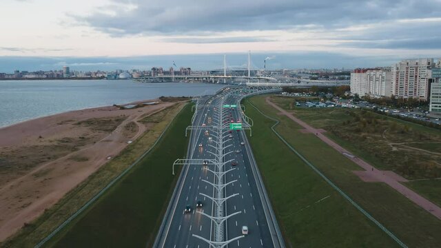 Dinamic aerial hyperlapse above Western High-Speed Diameter, ZSD. Cars moving fast on the multi lane highway. Pylon bridge and Zenit Arena stadium on background.