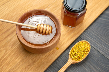 Fresh flower honey of different varieties, pollen with spoons on a wooden background. Organic...