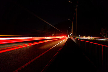 Long exposure of car’s lights on the night winding road with the silhouette of mountains. Long exposure photo of traffic.