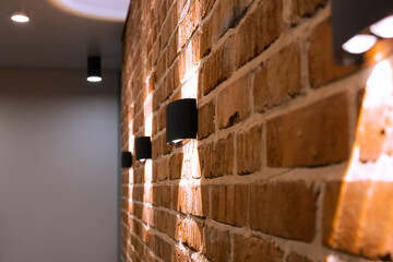 Decorative brown brick wall with lamps. Home interior, loft style, selective focus