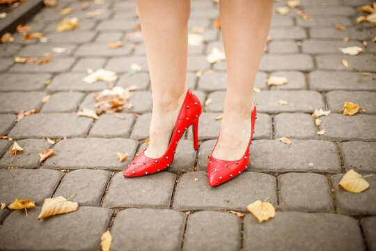 Female feet in red shoes on a stone pavement
