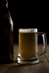 Bottle of craft beer and beer mug on a wooden table