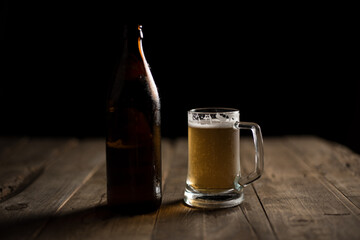 Bottle of craft beer and beer mug on a wooden table