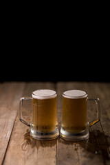 Two beer mugs at a wooden table