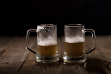 Two beer mugs at a wooden table