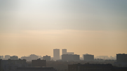 Aerial perspective of the morning haze in a large city. Panoramic view of the silhouettes of the roofs of houses of a large city separated into layers by an aerial perspective of the morning haze.