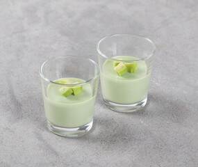 Avocado cream dessert, Panna Cotta in a glass on a light gray background