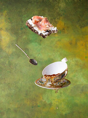 flying cups with hot tea on a green background and fish sandwich. Levitation.