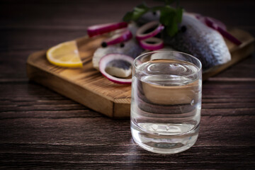Obraz na płótnie Canvas glass of vodka, herring on a wooden background