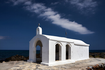 A white Orthodox chapel on a stone headland in the town of Georgioupoli on the island of Crete