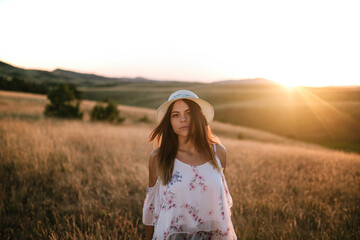 Fototapeta na wymiar Woman walking through a field of tall grass at sunset