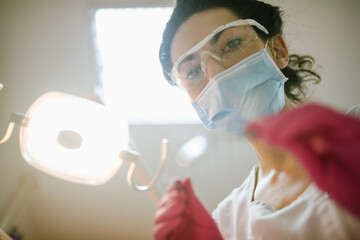 Female dentist in dental office examining patient teeth, patient point of view. 