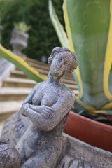 statue of a lady at the bottom of stone steps with green plant