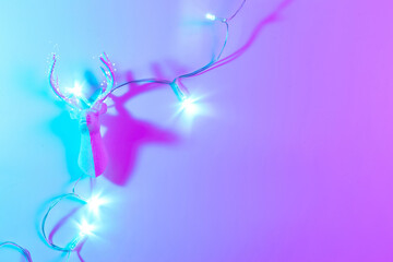 Stylish Christmas neon winter background. Holiday decoration bauble ball on neon gradient backdrop. Minimal abstract xmas reindeer. Happy new year copy space.