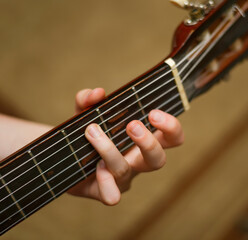 child's hand holds a guitar chord